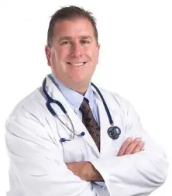 Doctor smiling doctor with gray hair with his arms folded over his chest
