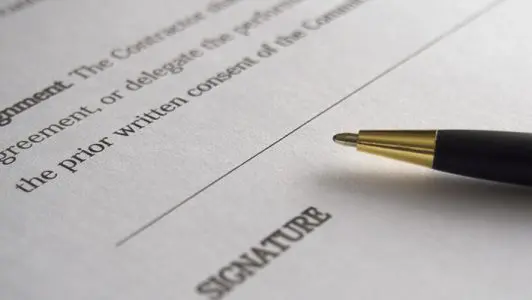 signature pen laying on a piece of paper that says signature